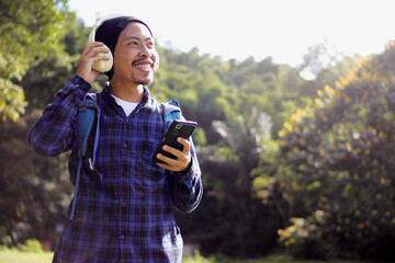 Young Asian man in a casual outfit, sporting a beanie, plaid shirt, backpack, and headphones,...