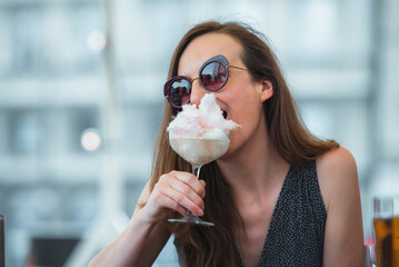 Woman eating pink candy floss from Prosecco drink 
