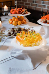Cheese canapés with grapes, fruit plates in the background.