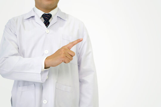 Healthcare professional in white lab coat stand in front of plain, white background, pointing to the right as if indicating a direction or highlighting a point of interest, explaining or presenting.