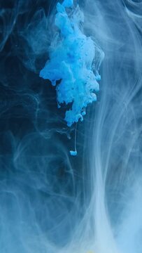 Blue ink flow in water over black background. Watercolor paint drops in water. Bright floating ink clouds underwater. Vertical video.