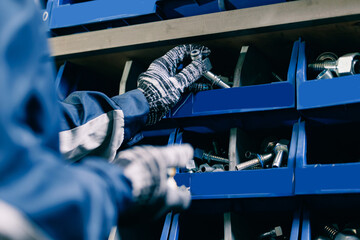 Industrial worker hold steel fittings for hydraulic hoses in manufacturing factory store