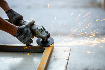 Grinding machine at work. Sparks fly from under the grinders, men's work. Dark background with copy space.