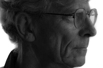 A low contrast closeup profile portrait of an old man with glasses