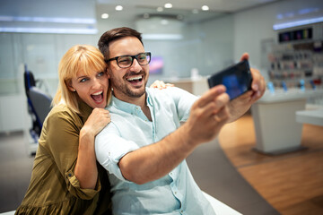 Smiling young couple looking at smartphone. Multiethnic people sharing social media on cell phone. - 780593402