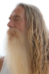 A portrait of an elderly bearded man with long hair and his eyes closed - 780594890