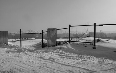 Destroyed fence after a strong storm. Element. Black and white. Snow. Ust-Kamenogorsk, kazakhstan