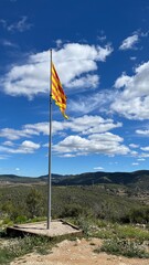 the flag of Catalonia on the background of the sky, on the mountain