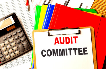 AUDIT COMMITTEE text on clipboard with calculator and color folder