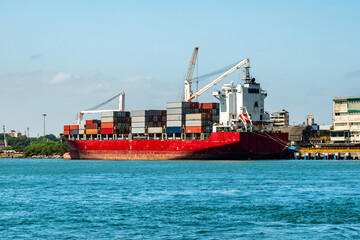 container vessel during discharging at an industrial port and move containers to container yard by trucks.