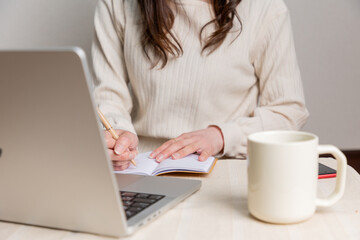 パソコンを見ながらメモをとる女性