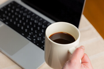 PC作業をしながらコーヒーを手にする女性の手