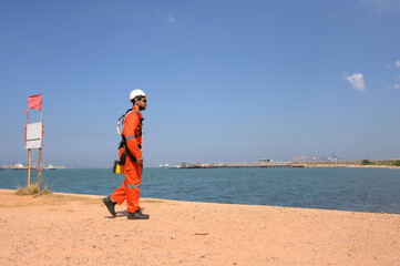 Male chemical engineer doing inspection work at a chemical storage tank on the seaside.