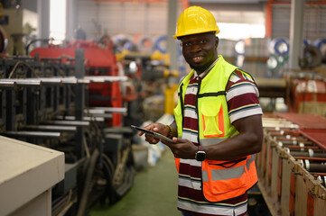 Male worker or technician working on tablet and checking mechanical equipment in factory