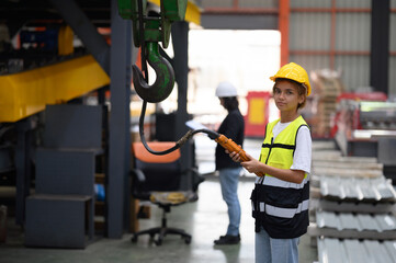 Female worker or technician working on tablet and checking mechanical equipment in factory