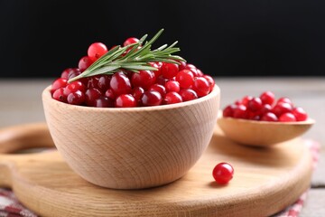 Fresh ripe cranberries and rosemary on wooden table, closeup