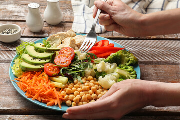 Balanced diet and healthy foods. Woman eating dinner at wooden table, closeup