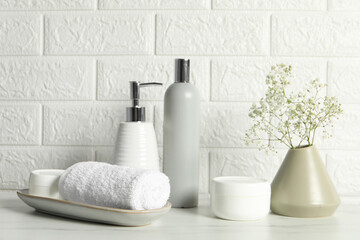 Different bath accessories, personal care products and gypsophila flowers in vase on white table...