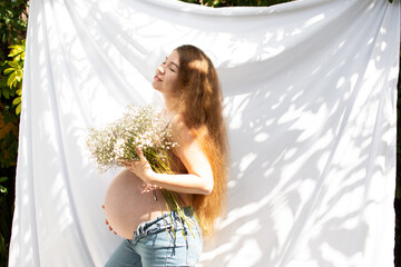 Happy Caucasian pregnant woman with long hair holding flower bouquet. Baby's breath flowers. 37...