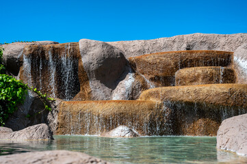 Künstlich angelegter Wasserfall in einem dekorativen Teich im eigenen Garten