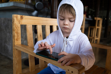 Kid gaming using smartphone while waiting in restaurant. - 780613282