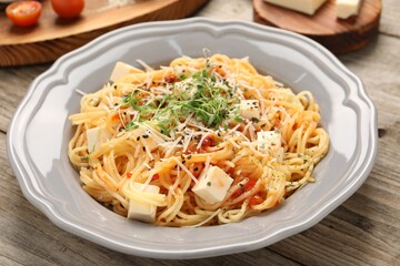 Vegetarian meal. Tasty pasta with fresh microgreens and cheese on wooden table, closeup