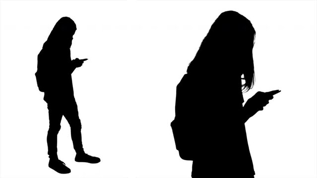 Male Teenager Silhouette Using Smartphone Full Body Medium Shot. Profile of a long haired teenager silhouette student with a backpack using a smartphone. Full body and medium shot