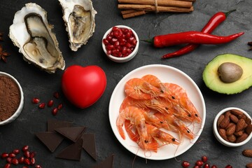 Natural aphrodisiac. Different food products and heart model on black table, flat lay
