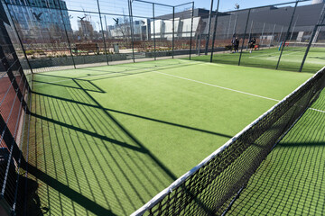 Landscaped areas of a residential development with a tennis court with high Plexiglas and metal...