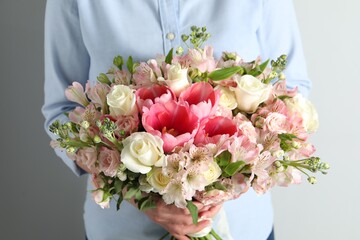 Woman with beautiful bouquet of fresh flowers on light background, closeup