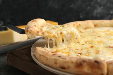 Taking piece of delicious cheese pizza at table, closeup