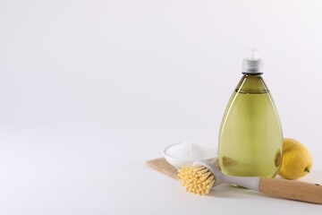 Bottles of cleaning product, brush, baking soda and lemon on white background