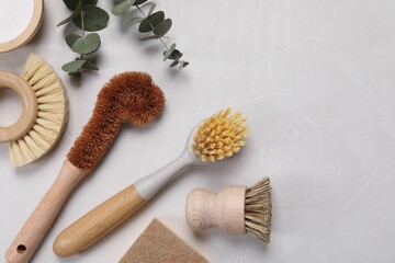 Cleaning brushes, baking soda, soap bar and eucalyptus on white table, flat lay. Space for text