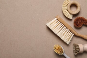 Cleaning brushes on pale brown background, flat lay. Space for text