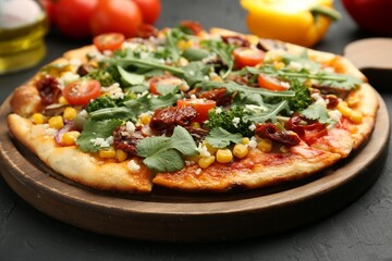 Delicious vegetarian pizza with cheese, vegetables and greens on black table, closeup