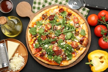 Delicious vegetarian pizza, ingredients, cutter and grater on black table, flat lay