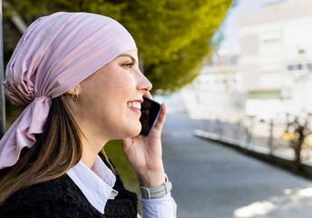 Overcoming cancer! Photo of a profile portrait of an adult woman with a pink scarf is talking on...