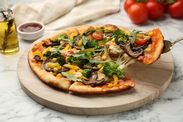 Taking piece of delicious vegetarian pizza at white marble table, closeup