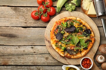 Delicious vegetarian pizza and ingredients on wooden table, flat lay. Space for text