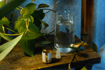 Insomnia concept. Sleeping pills and glass of water on bedside table at night.