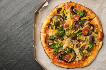 Delicious vegetarian pizza with mushrooms, cheese and vegetables in box on black table, top view. Space for text