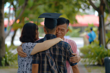 Naklejka premium Asian graduate in caps with tassels hugs his parents. End of study, graduation.