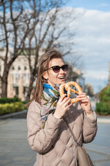 Beautiful young woman holds bagel outdoor on the street in Belgrade, Serbia