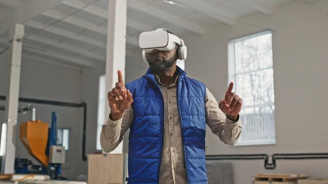 Close-up portrait of nice employed busy bearded African-American male during interesting work process. Innovative original worker using contemporary latest up-to-date VR device.