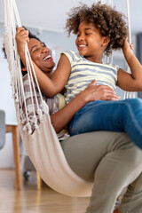 Portrait of happy black woman and her cute preteen daughter having fun together at home - 780622619