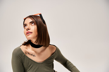 A brunette woman exudes style in a green shirt with a black tie around her neck, in a studio...