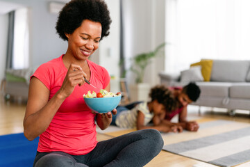 African american woman with family on background eating a healthy salad after workout. Fitness - 780626847
