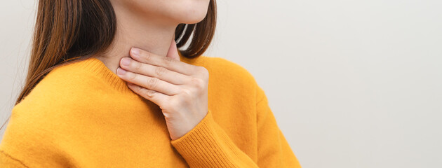 Sore throat in flu season. Young asian woman touching her neck and feeling pain in throat in the bedroom at home. - obrazy, fototapety, plakaty
