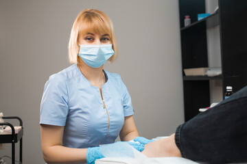 Portrait of podologist podiatrist in face mask and uniform at the clinic. 