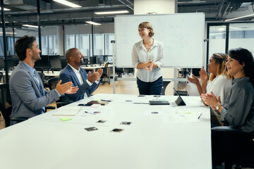 Group of happy multiracial business people applauding around conference table in office - 780635636